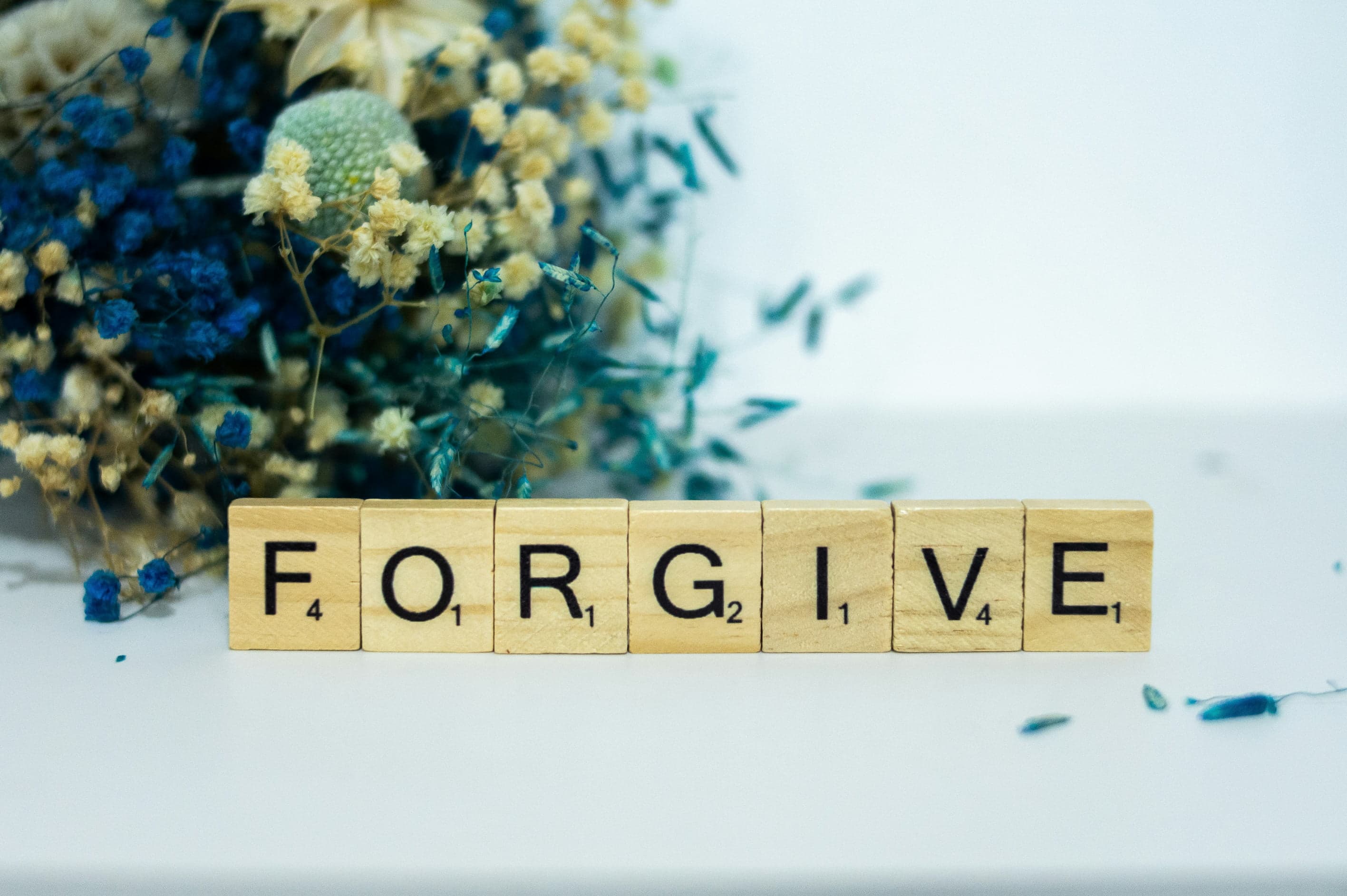 Lettres de Scrabble formant le mot FORGIVE sur fond clair
